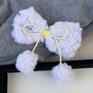 Détail de pince à cheveux nœud en peluche lavande avec carreaux jaunes et pompons