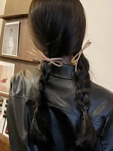Close-up of elegant faux leather bow hair tie on braided hair with minimalist Korean style