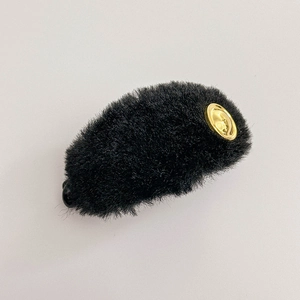 Close-up of black plush hair clip texture with elegant gold metal circular accents