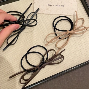 Three minimalist bow hair ties in black, khaki and brown PU leather on a beige tray