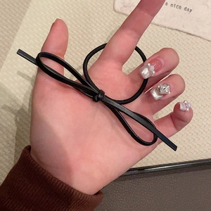 Detailed view of handmade black matte faux leather bow hair tie held in hand