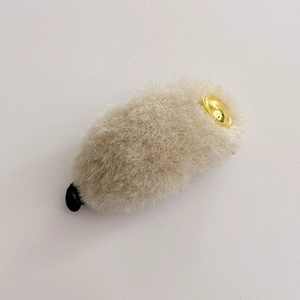 Macro shot of plush hair clip with beige faux fur and golden metal round accent