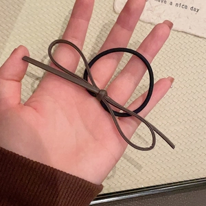 Detail of high-elastic black hair tie with a soft brown leather bow for ponytail styling