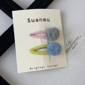 Close-up of colorful felt ball hair clips with metal BB clips on a display card