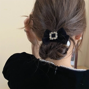 Detail van een zwarte fluwelen strik met een sprankelend strass-midden op een model