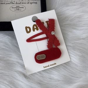 Red plush bow hair clip set with rhinestones on a white display card for kids