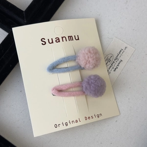 Close-up of wool felt BB hair clips with soft macaron colored pom poms on a display card