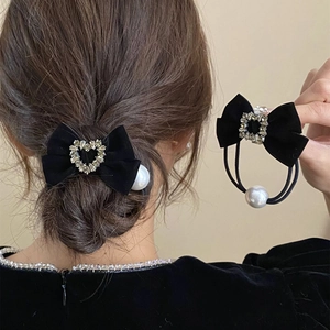 Detail van zwarte fluwelen haarstrikken met hartvormige strass en witte parelhanger
