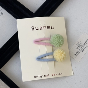 Detail view of colorful wool felt hair clips with soft pom-poms on decorative card