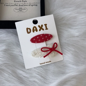 Detail view of red bow and plush hair clips on brand display card for girls