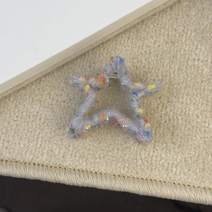Vue détaillée de la pince à cheveux en laine en forme d'étoile avec fil coloré et paillettes