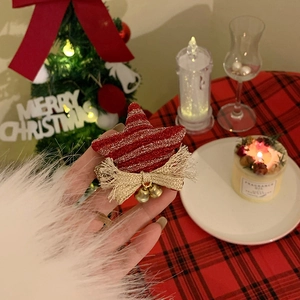 Detail of red glitter star hair accessory with golden bow and bells held in hand