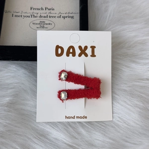 Detail of red plush hair clips featuring sparkling square rhinestones on a white card
