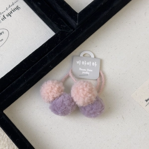 Detail of pink and purple plush pom pom hair ties with high-elastic rope on display card