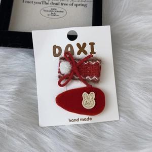 Detail of red plush bow hair clips with white pom-poms and rabbit patch on display card
