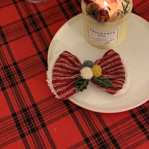 Detail of red glitter striped Christmas bow hair clip with plush fur and holly leaves
