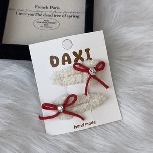 Detail of plush white BB clips with red ribbon bows and sparkling rhinestone accents