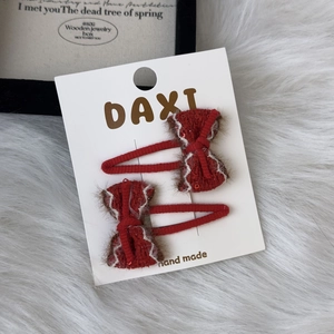 Detail of red knitted bow hair clips with white stitching and sparkling sequins in a 2-piece set