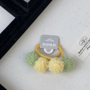 Close-up of pastel pom-pom hair ties on a textured fabric background for girls