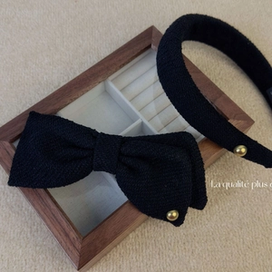 Set cerchietto e fermaglio a fiocco in tweed nero con bordi dorati su fondo morbido