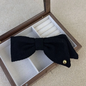 Dettaglio del fermaglio per capelli a fiocco in tweed nero con perla dorata lucida