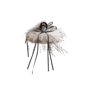 Pince à cheveux en plumes grises avec ruban noir et breloque cœur doré sur fond blanc