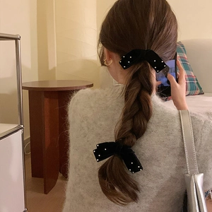 Elegant black velvet bow hair clip with pearls shown on a braided hairstyle