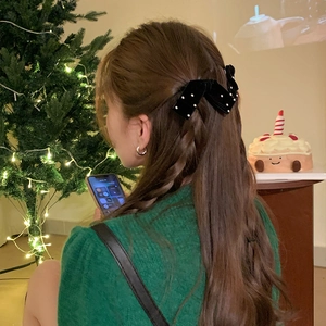 Elegant black bow hair clip with white dots on model for Christmas holiday party style