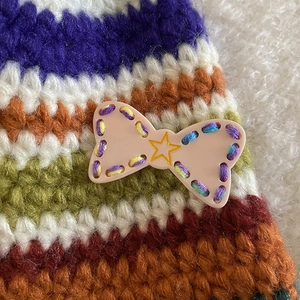 Close-up of handmade knitted bow clip with colorful yarn texture and a pink heart star charm