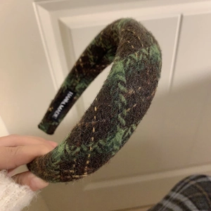 Detailed close-up of handmade green and brown plaid wool headband with brand label