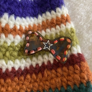 Close-up of tortoise shell bow hair clip with hand-stitched edges and silver star detail