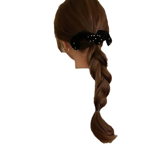 Elegant black velvet bow hair clip with white pearls on model with brown braided hair