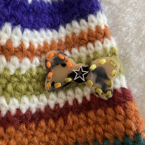 Detail of colorful knitted hair clip with tortoiseshell bow and silver star ornament
