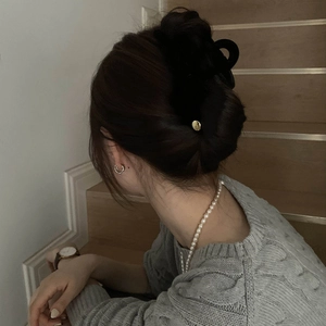 Pince à cheveux noire élégante avec accent doré sur une coiffure en chignon bas