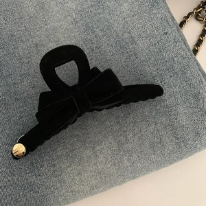 Détail d'une pince à cheveux en velours noir avec pendentif doré sur denim