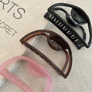 Three elegant French acetate hair claws in black, brown, and pink with a gold logo