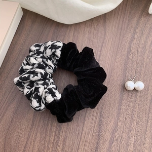 Detail of houndstooth and black velvet patchwork scrunchie on an elegant background