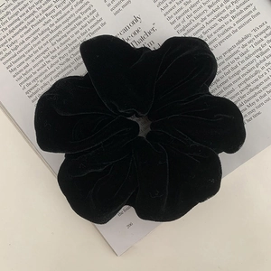 Detailed view of a thick black velvet scrunchie placed on an open magazine page