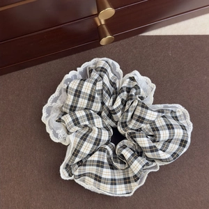 Detailed view of checkered scrunchie with white lace trim on a vintage wooden surface