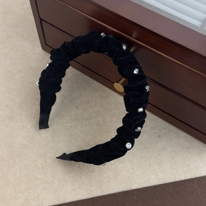 Detail of pleated black velvet headband with sparkling rhinestones and retro texture