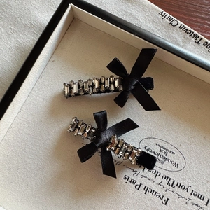 Pair of vintage black velvet bow hair clips with silver rhinestones on a retro box