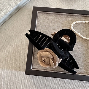 Détail d'une pince à cheveux en velours noir avec fleur de camélia et perles
