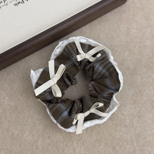 Close-up of vintage plaid hair scrunchie with lace edges and delicate white ribbon bows