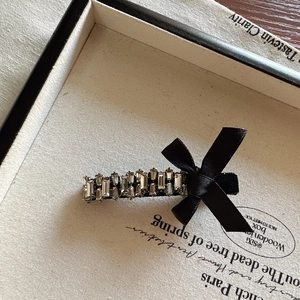 Detailed macro view of black satin bow hair clip with luxury rhinestone inlay decoration