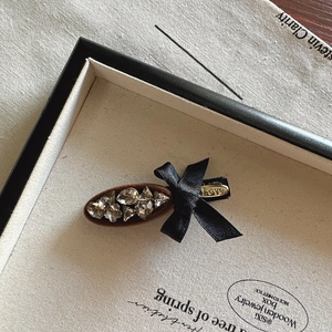 Elegant bow hair clip with sparkling rhinestones and gold LOVE lettering on a tray