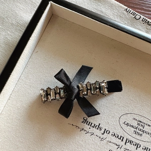 Detailed macro view of black velvet bow hair clip with sparkling crystals in a gift box