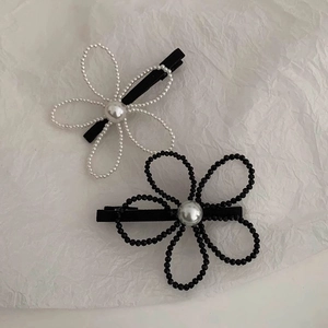 Elegant pair of pearl flower hair clips in black and white styles on matte metal base