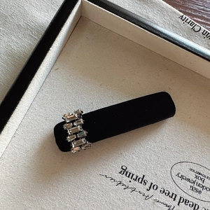 Macro detail of a black velvet hair clip with sparkling rectangular rhinestones
