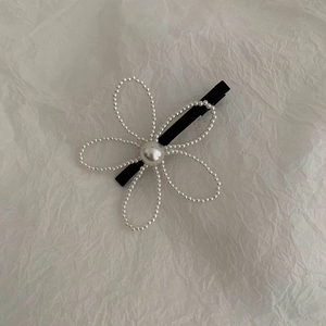 Close-up of pearl flower hair clip featuring white imitation petals and black duckbill base