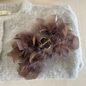 Elegant French style brown ostrich feather hair claw clip for women over grey knit background